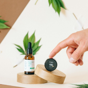 Minimalist shot of CBD oil and cream on wooden platforms with cannabis leaves for wellness.