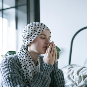 Woman wearing polka dot scarf, reflecting and praying, symbolizing hope and recovery.